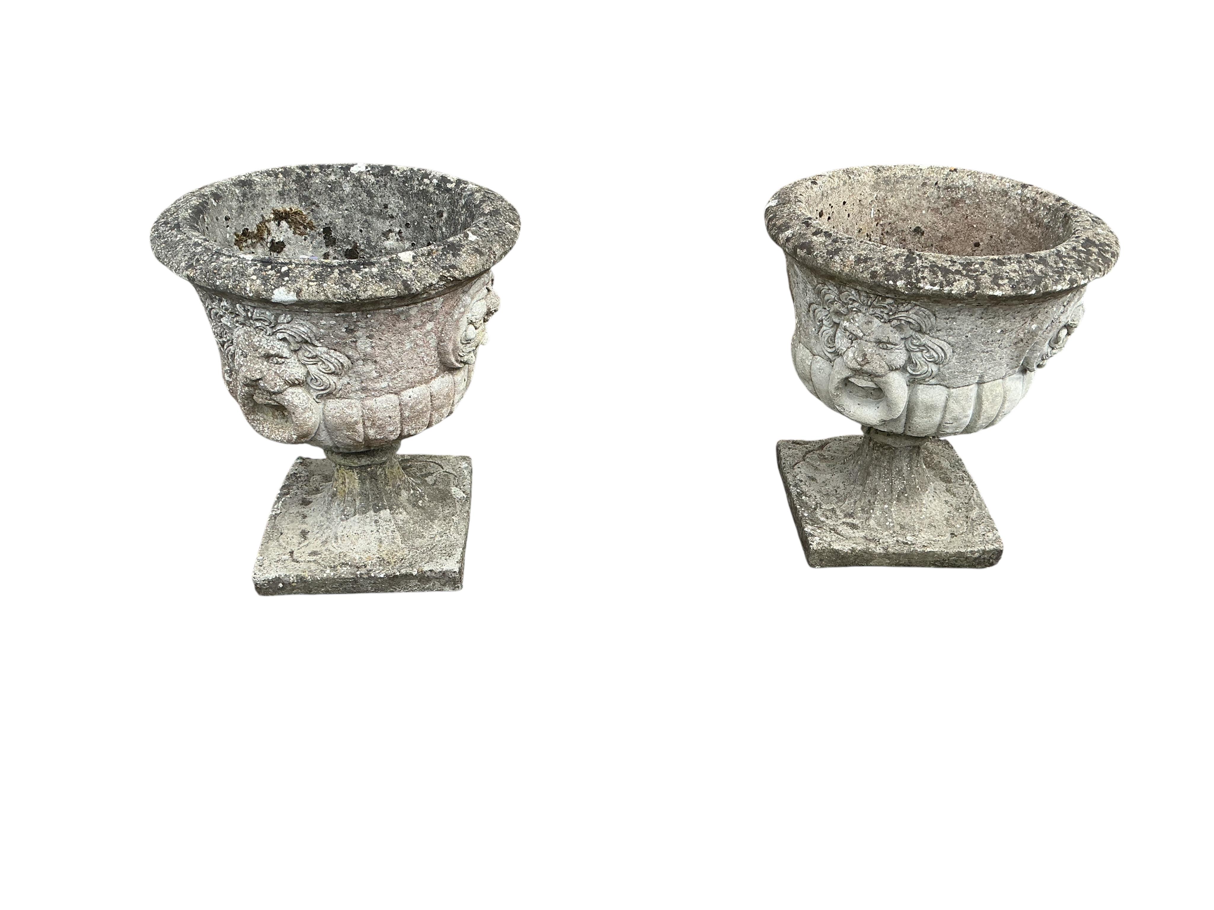 A pair of circular reconstituted stone garden urns with moulded lion mask ring decoration, diameter 53cm, height 60cm